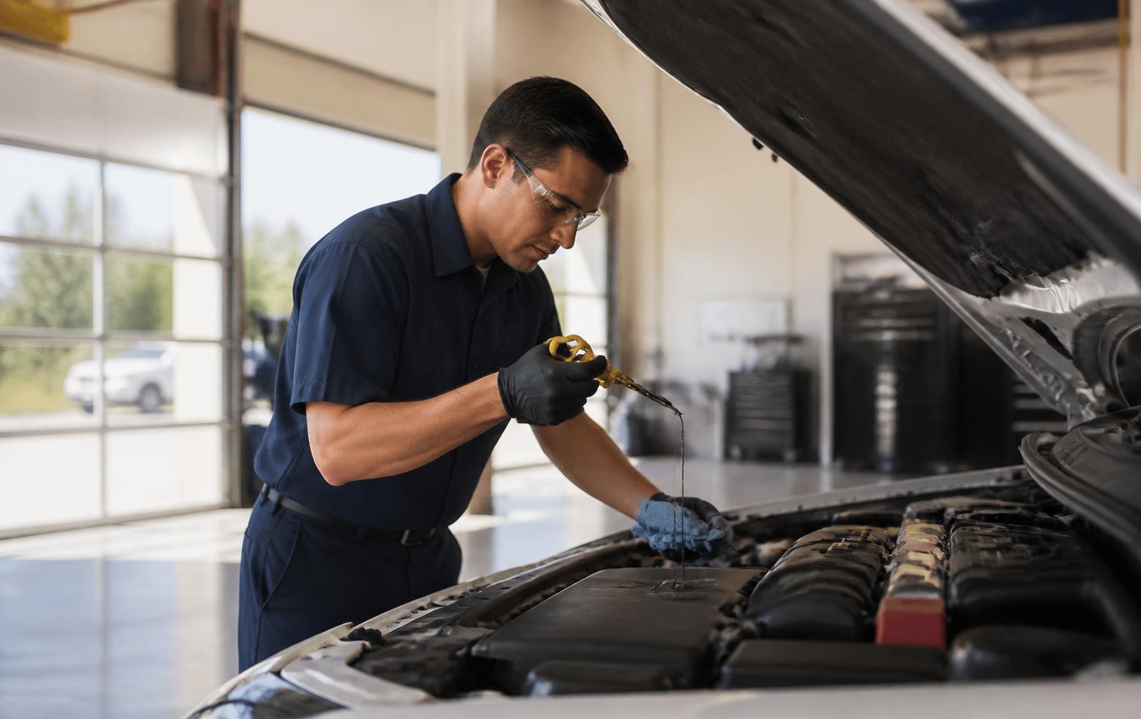 Technician checking engine oil on a vehicle inside a clean quick-lube service bay